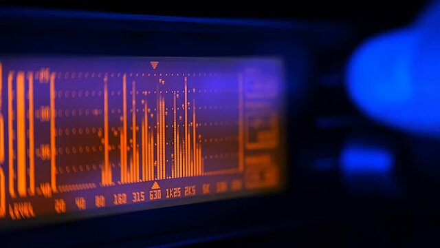 The hand turns the controls on the front panel of the equalizer and adjusts the volume level, the dynamics of the music, the priority of the selected frequencies in the range. Closeup