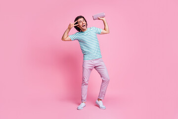 Full length photo of dancing young gentleman wear casual outfit holding modern device showing v-sign isolated pastel color background