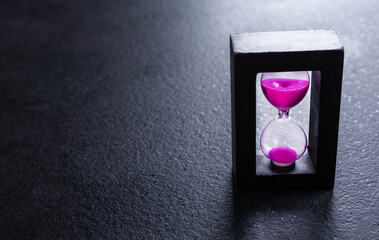 Hourglass on a dark background of volcanic stone