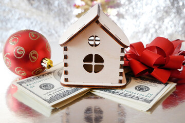wooden house model, gold chocolate coins and new year decorations on shining background with copy...