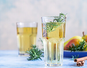 Pear cider cocktail with rosemary in tall glasses and bottle and fresh pears, blue stone background. Summer refreshment drink.