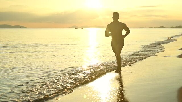 Silhouette healthy guy workout on the beach with sunset view. Recreation and relaxing on summer holiday.