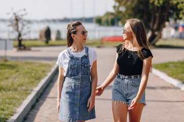 two young pretty girls on a walk in the park. a sunny summer day, joy and friendships.
