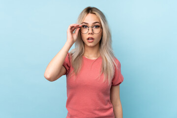 Fototapeta premium Teenager girl over isolated blue background with glasses and surprised