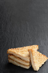 Sesame seeded prawn toasts on black stone background