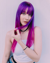 Young girl with vibrant purple dyed hair posing with a white background