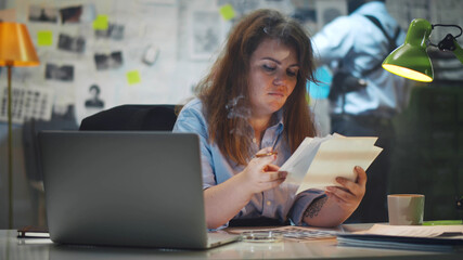 Private detective woman examining photos of criminal case and smoking in office