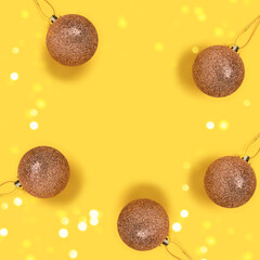 Round frame made of golden Christmas baubles on a yellow background. Greeting card template.