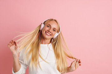 Happy beautiful girl listening music with headphones and dancing