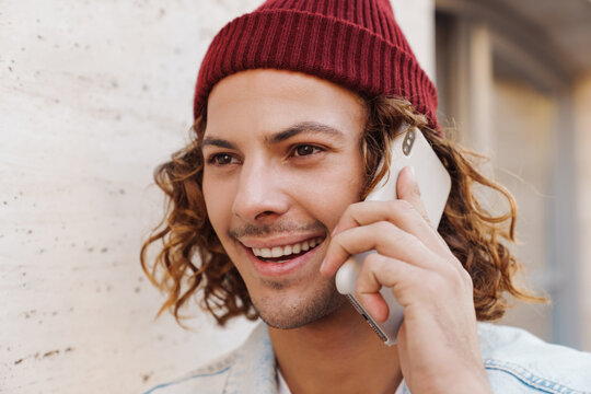 Happy young curly man talking by mobile phone