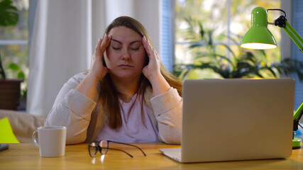 Tired fat woman suffering eyestrain working on laptop at home