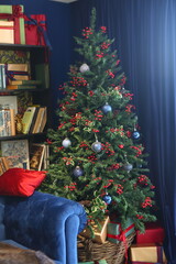 Celebratory New Year tree decorated with beautiful fur-tree toys and Christmas gifts in gift packages and celebratory boxes