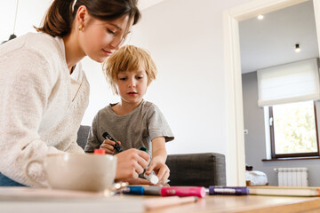 Obraz na płótnie Canvas Pretty woman drawing at home with her son