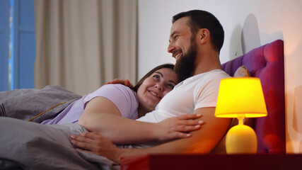 Happy young couple hugging in bed and communicating