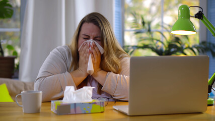 Obese woman working from home feeling sick and sneezing in tissue