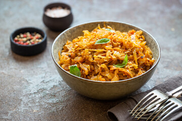 Stewed or braised cabbage served in a bowl on dark stone background, close up