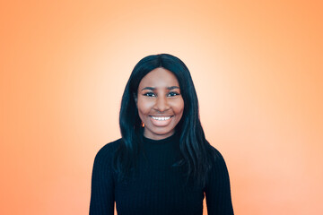 portrait of a young smiling carefree black woman on orange background