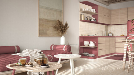 Cosy wooden sustainable kitchen and living room in red tones with modern sofa and coffee tables. Tea time, glass teapot and teacup, snacks. Environmental friendly interior design