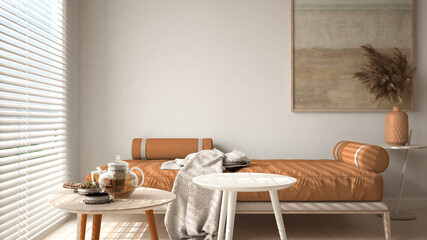 Cosy wooden sustainable living room in orange tones with modern sofa with blanket and coffee tables. Tea time, glass teapot and teacup, snacks. Environmental friendly interior design
