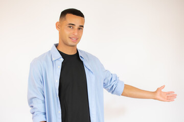 friendly young man pointing to his side and looking into the camera. isolated on white background