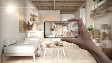 Hand holding smart phone, AR application, simulate furniture and interior design products in real home, architect designer concept, blur background, living room with sofa and kitchen