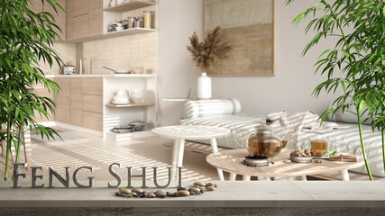 Wooden vintage table shelf with pebble balance and 3d letters making the word feng shui over blurred cosy sustainable kitchen and living room with sofa, zen concept interior design