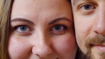 Macro shot of cheerful man and woman looking at camera and smiling