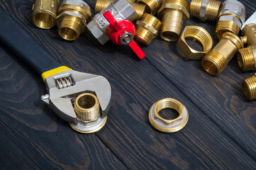 A set of brass fittings and an adjustable wrench on vintage boards. Plumber master work environment
