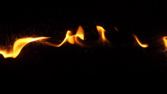 Slow motion speed closeup scene on  burning pattern rise up on black grunge floor background, fast spread of blue hot flame above fuel surface, blasting stream of fire ignite on petroleum