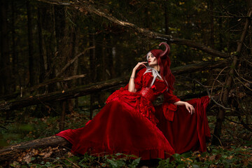 Stylish and fashionable model girl in the image of Maleficent posing among mystic forest -...