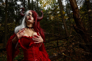 Stylish and fashionable model girl in the image of Maleficent posing among mystic forest -...
