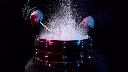 Freeze motion of drummer hitting drum with water splashes