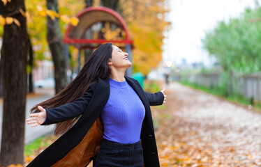 Portrait of a young woman in autumn. She turns with open arms.