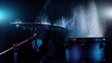 Freeze motion of drummer hitting drums with water splashes