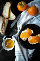 Gourmet bruschettas with camembert cheese or brie cheese, and honey, and persimmon on a wooden board. Healthy food, dessert.