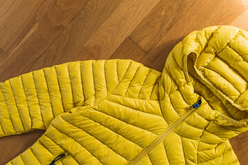 Yellow anorak for hiking on a wooden floor background. © Erika Anes