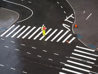 Worker standing alone at a crossroad, Stop sign,  pedestrian crossing under the rain, corner intersection in New York, lines, curves