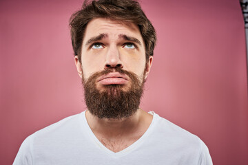 bearded man in white t-shirt emotions displeased facial expression studio pink background