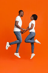 Fototapeta na wymiar Black couple in love holding hands and jumping up