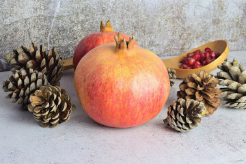 Autumnal presentation, pomegranate fruits with pinecone around it, on stone base
