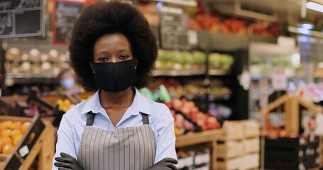 Close up portrait of happy African American female Worker in black mask and gloves standing in...