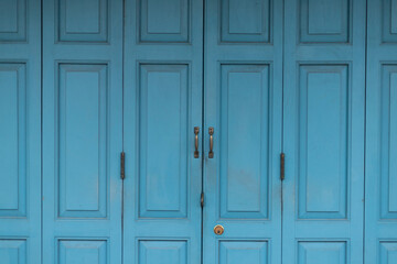 Closeup detailed texture of blue paint peeling off of an old wooden door.