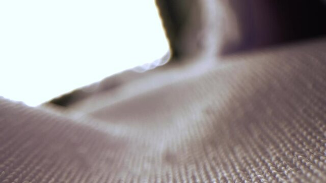 Motion along light beige knitted fabric against bright light