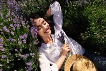 Young woman lying in lavender field on summer day