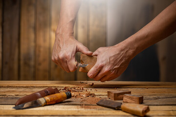 Craftsman carving tools with a chisel  carving knife a piece of dark wood on carpentry workbench 