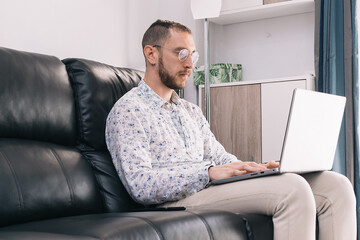 Young man making a call using a smartphone and laptop for work. Concept working home during 2020 covid coronavirus pandemic