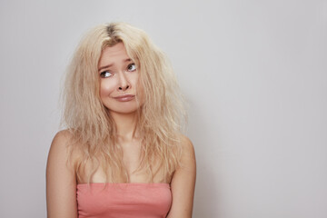 Beautiful woman with messed up hair. Unhappy grimacing face. Blond bleaching hairstyle with problem...