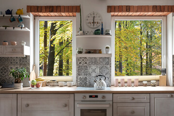 Interior of kitchen with view from window on forest, white wooden furniture and bricks as a decoration. Scandinavian style in a cottage with countertop and plant. - obrazy, fototapety, plakaty