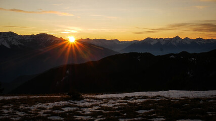 Sun setting beautifully behind rugged mountain ranges in late fall (BC, Canada).