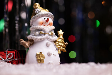 New Year card with a snowman on a background of colored bokeh.
